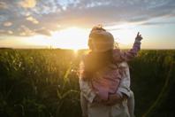 Roya holding a child in her arms with the child pointing to the sky